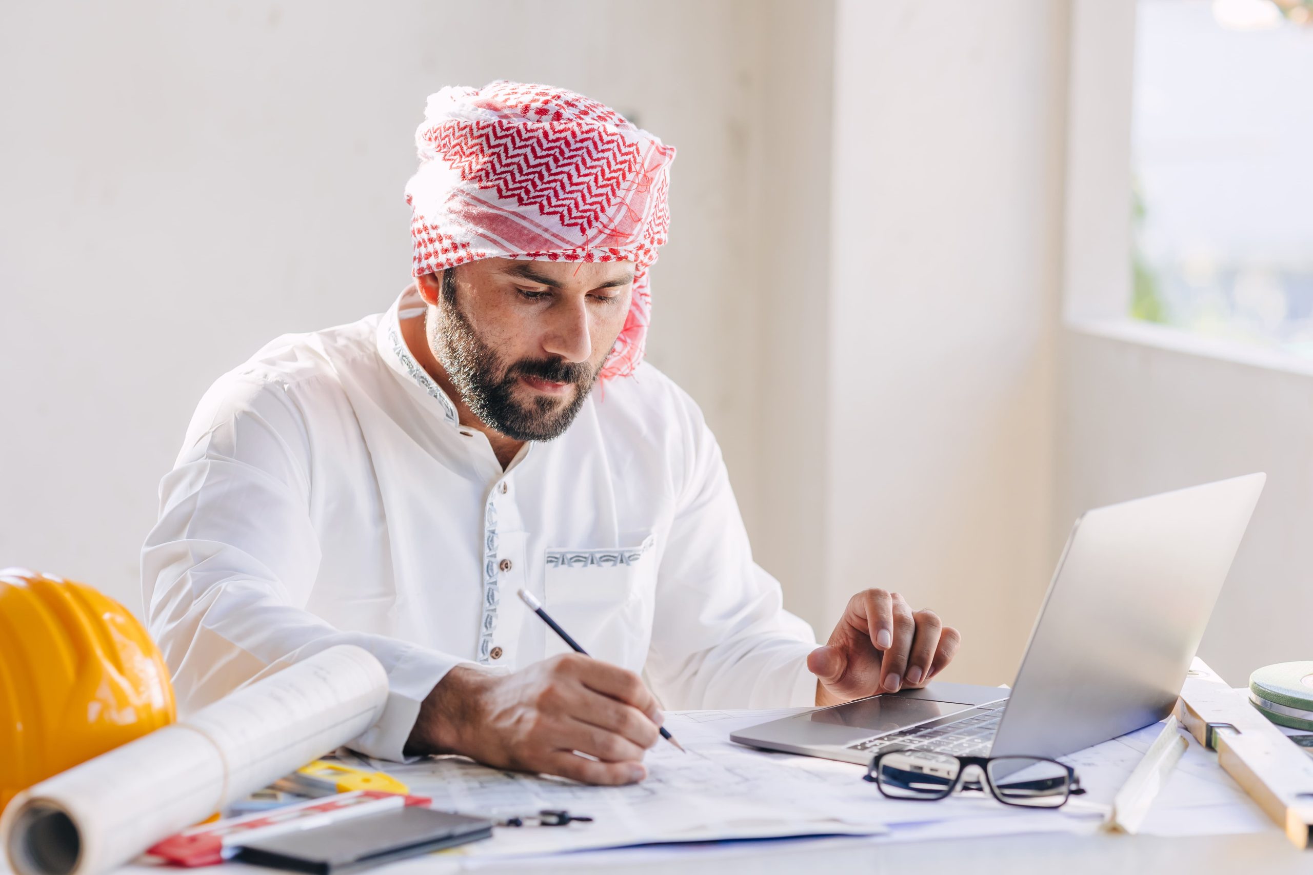 Arab construction engineer and architect reviewing building designs at a desk