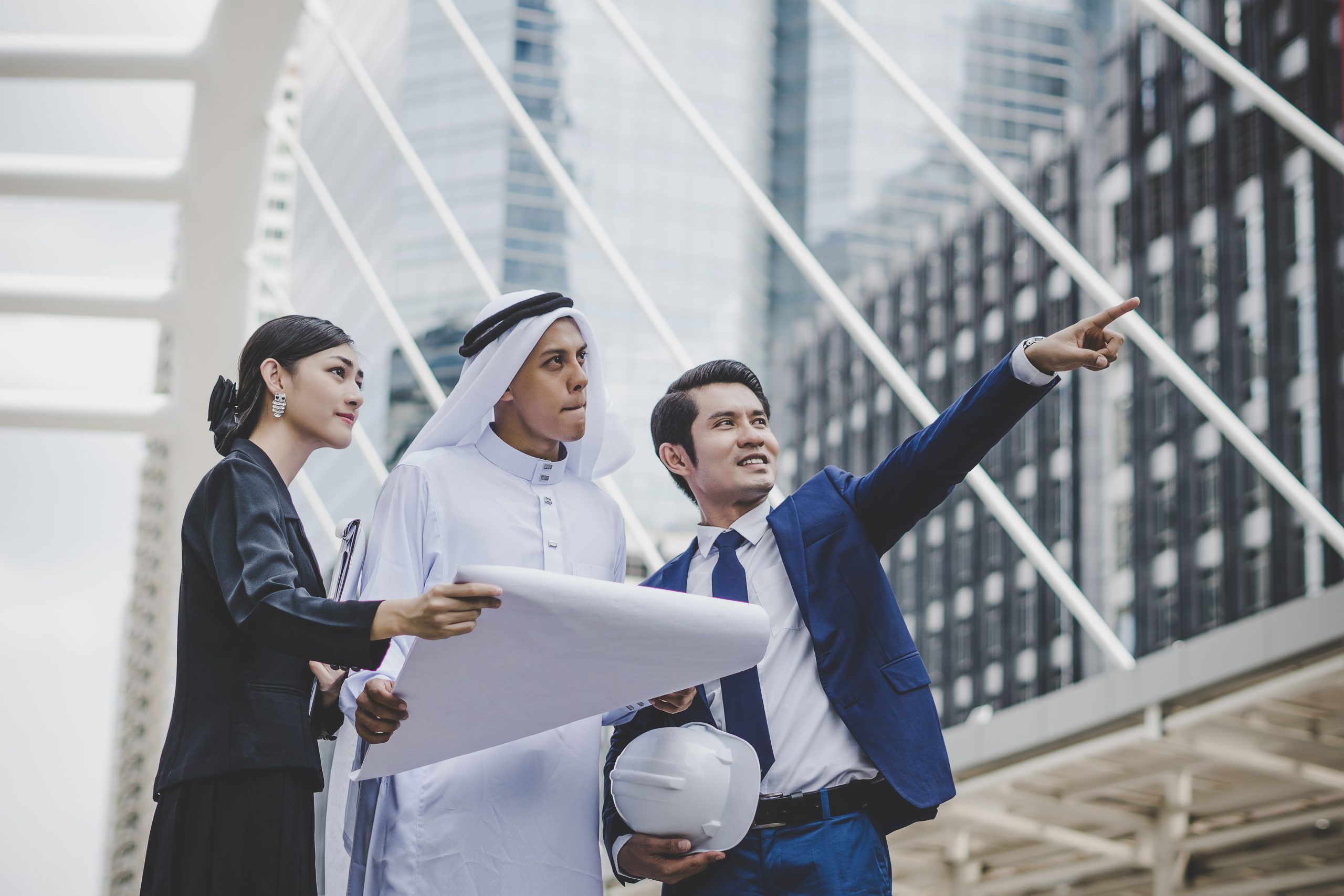 Business team examining building plans in front of a modern city skyscraper