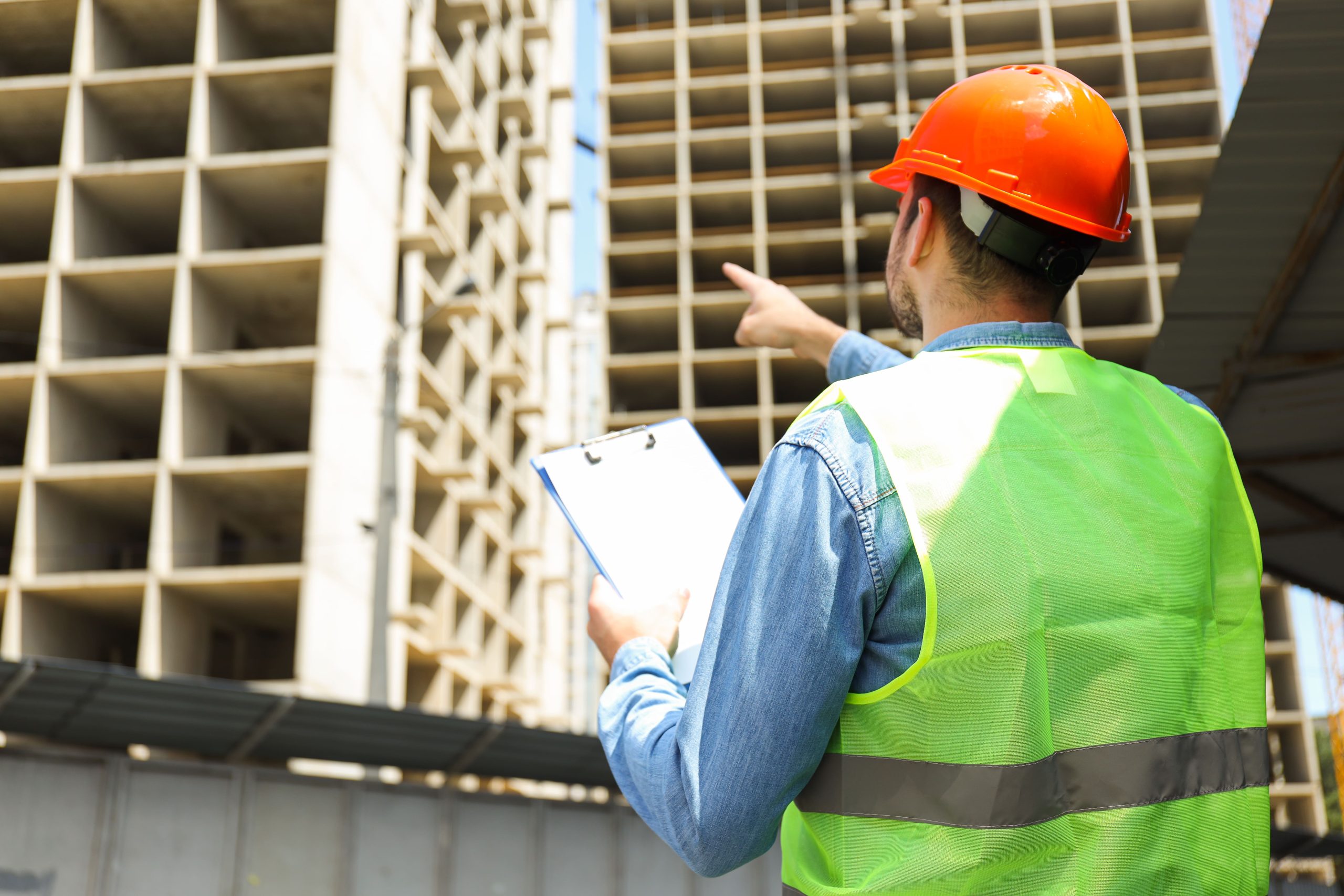 Construction inspector in safety vest reviewing building development at a construction site